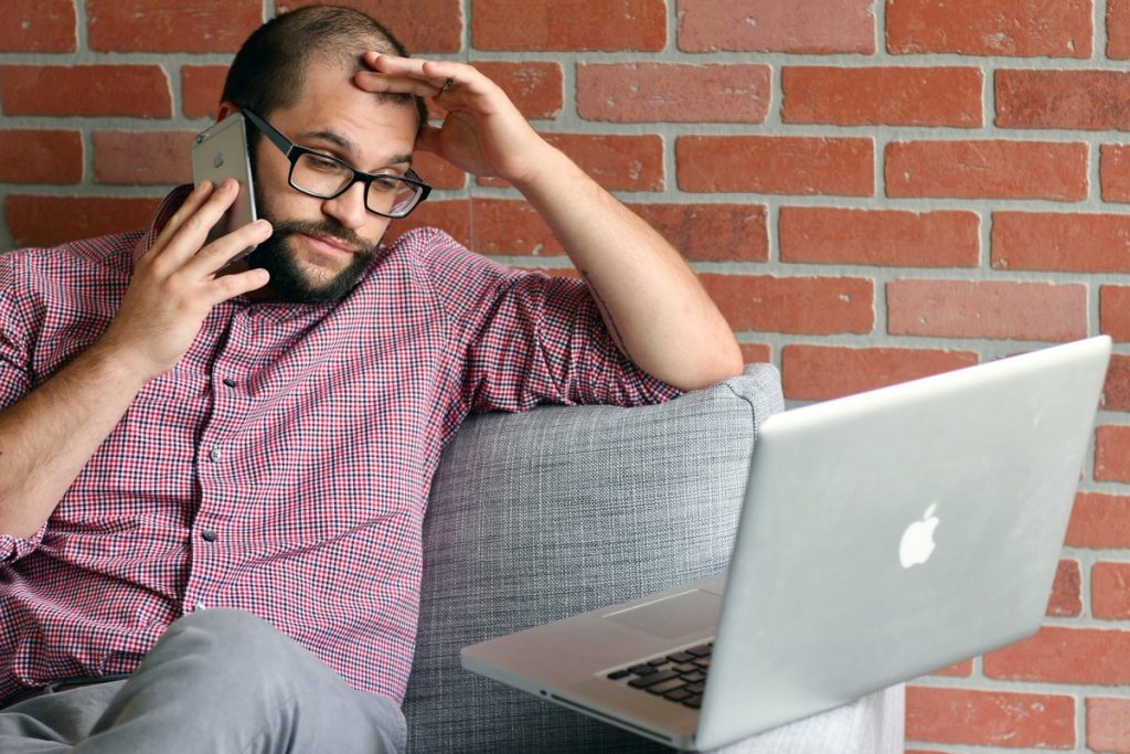 Mann am Computer gleichzeitig telefonierend