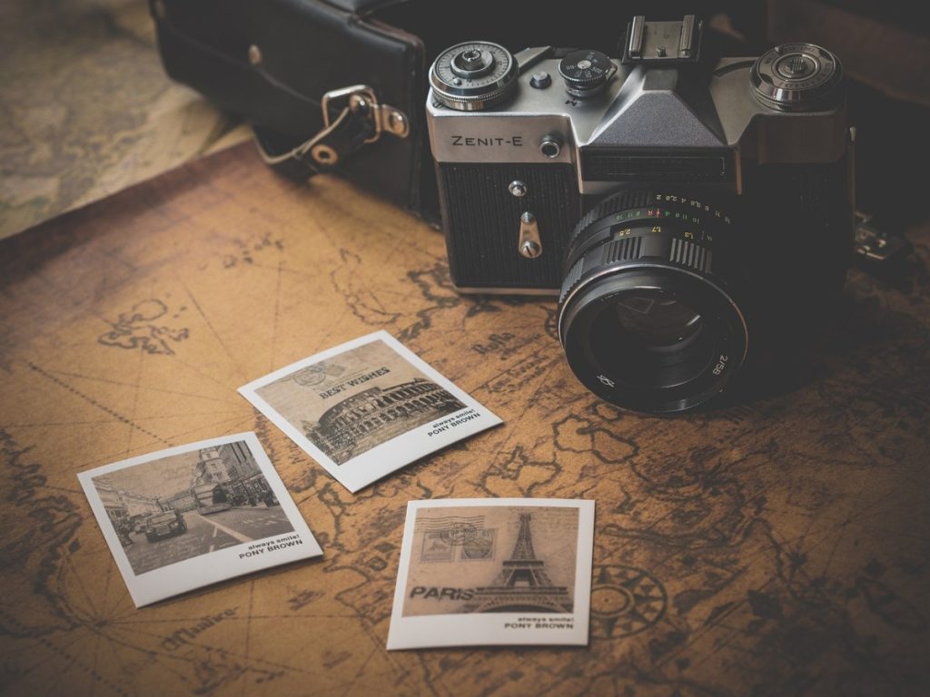 Fotoaparat und ausgedruckte Fotos von Reisezielen auf einem Tisch