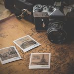 Fotoaparat und ausgedruckte Fotos von Reisezielen auf einem Tisch