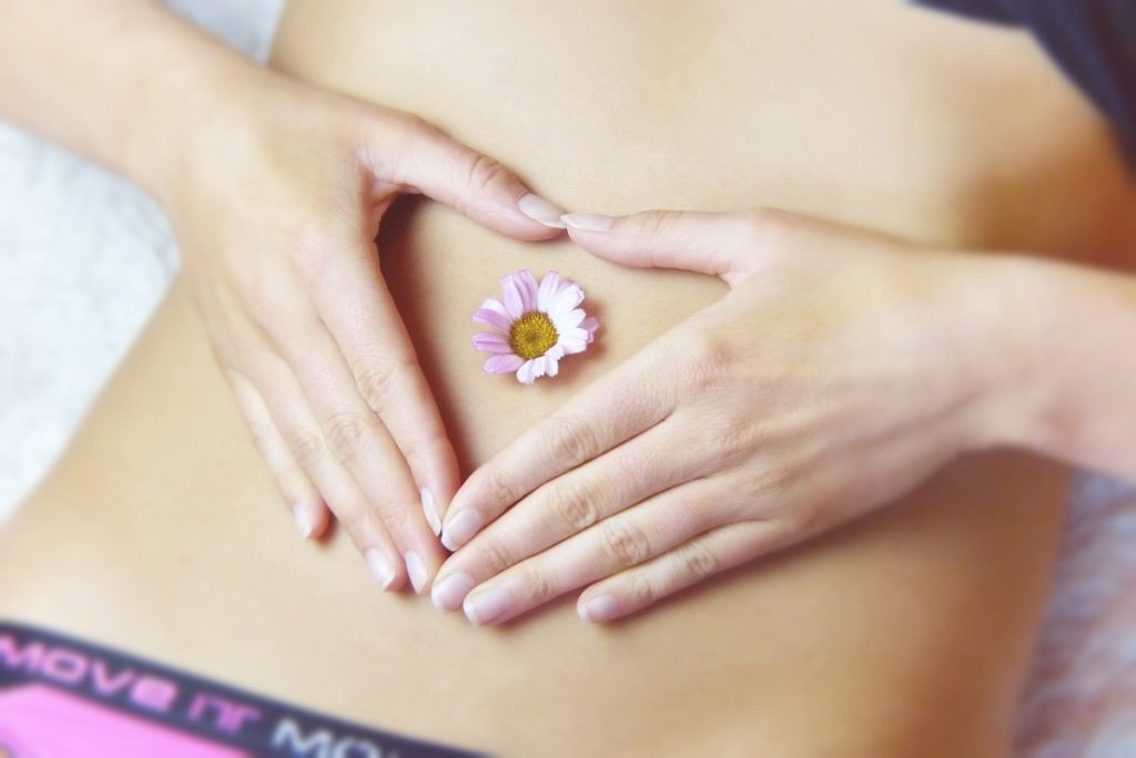 Bauch einer Frau mit einer Blüte im Bauchnabel